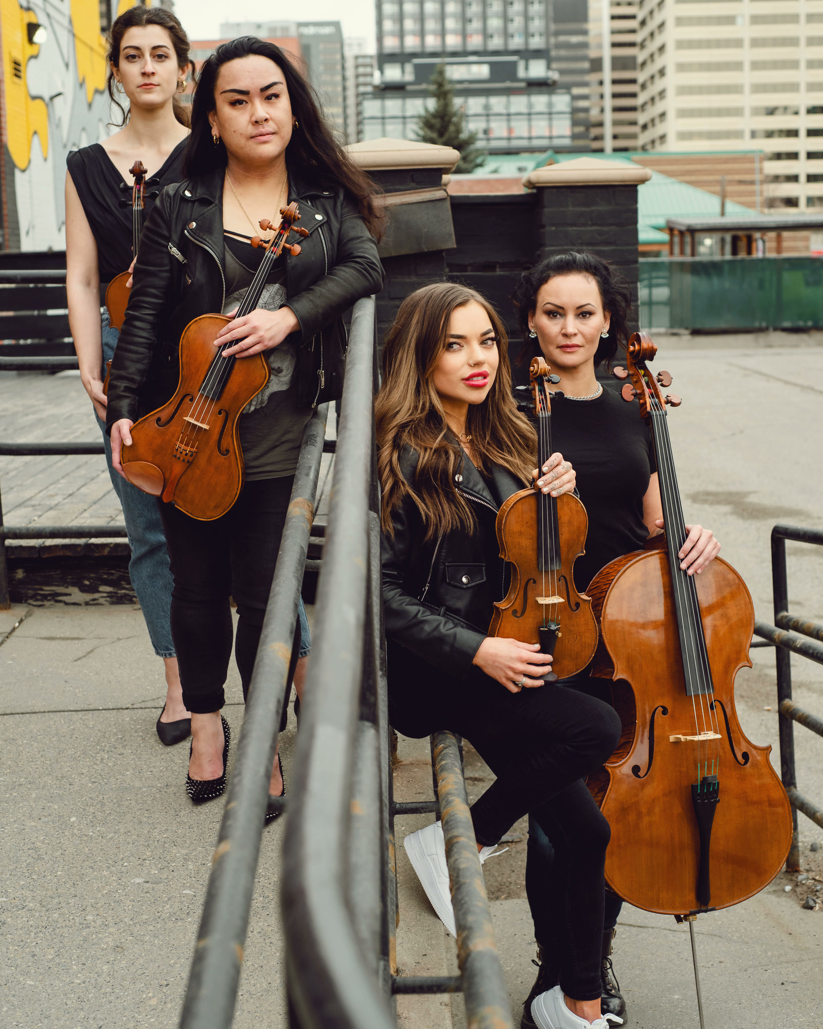 Four string players with their violins, viola and cello on a city rooftop